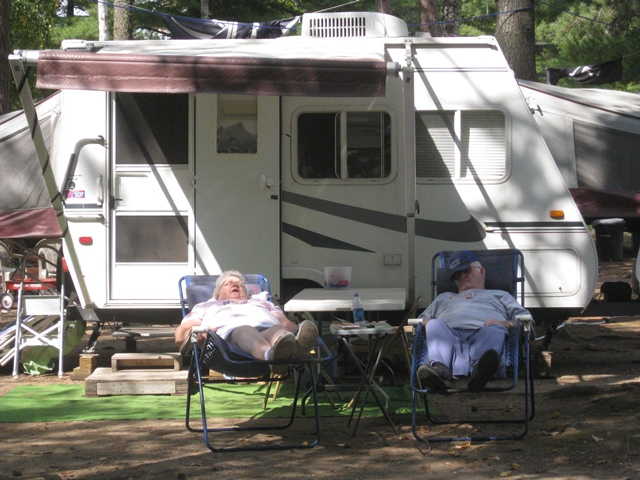 Chain O' Lakes Campground -- couple snoozingi n front of their RV